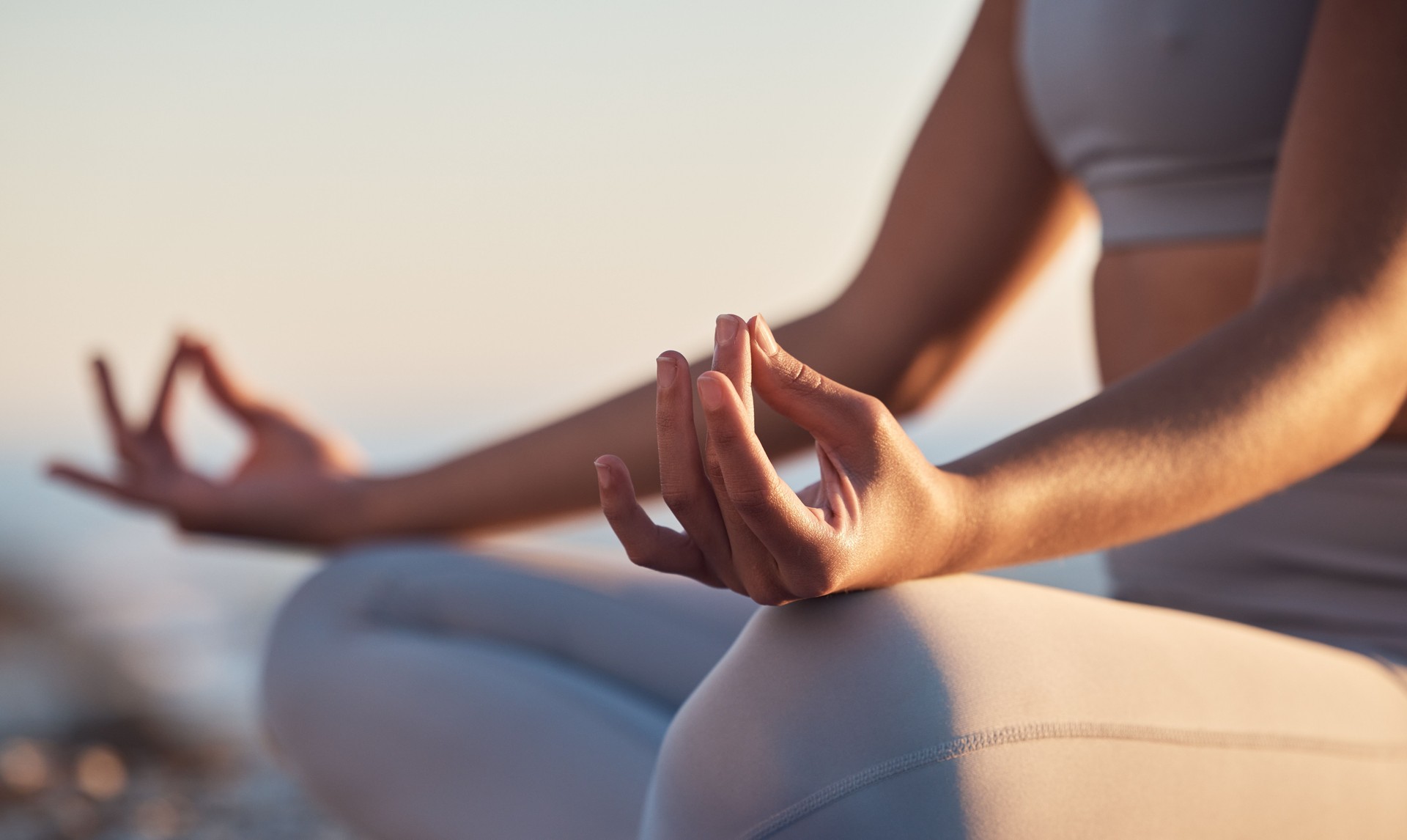 Woman, hands or lotus pose meditation on sunset beach, ocean or sea in mental health, mind training or chakra balance. Zoom, peace or zen yogi in calm mudra, relax yoga wellness or sunrise gratitude